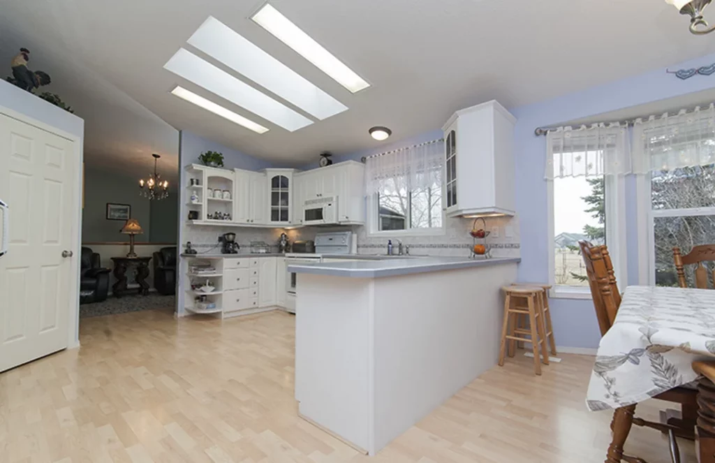 Cocina moderna con isla central blanca, barra con taburetes y almacenaje integrado.